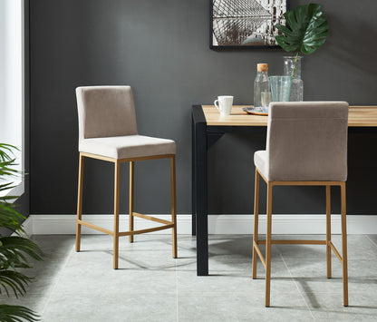 Two Diego 26-inch grey velvet counter stools with aged gold metal legs styled in a dining room