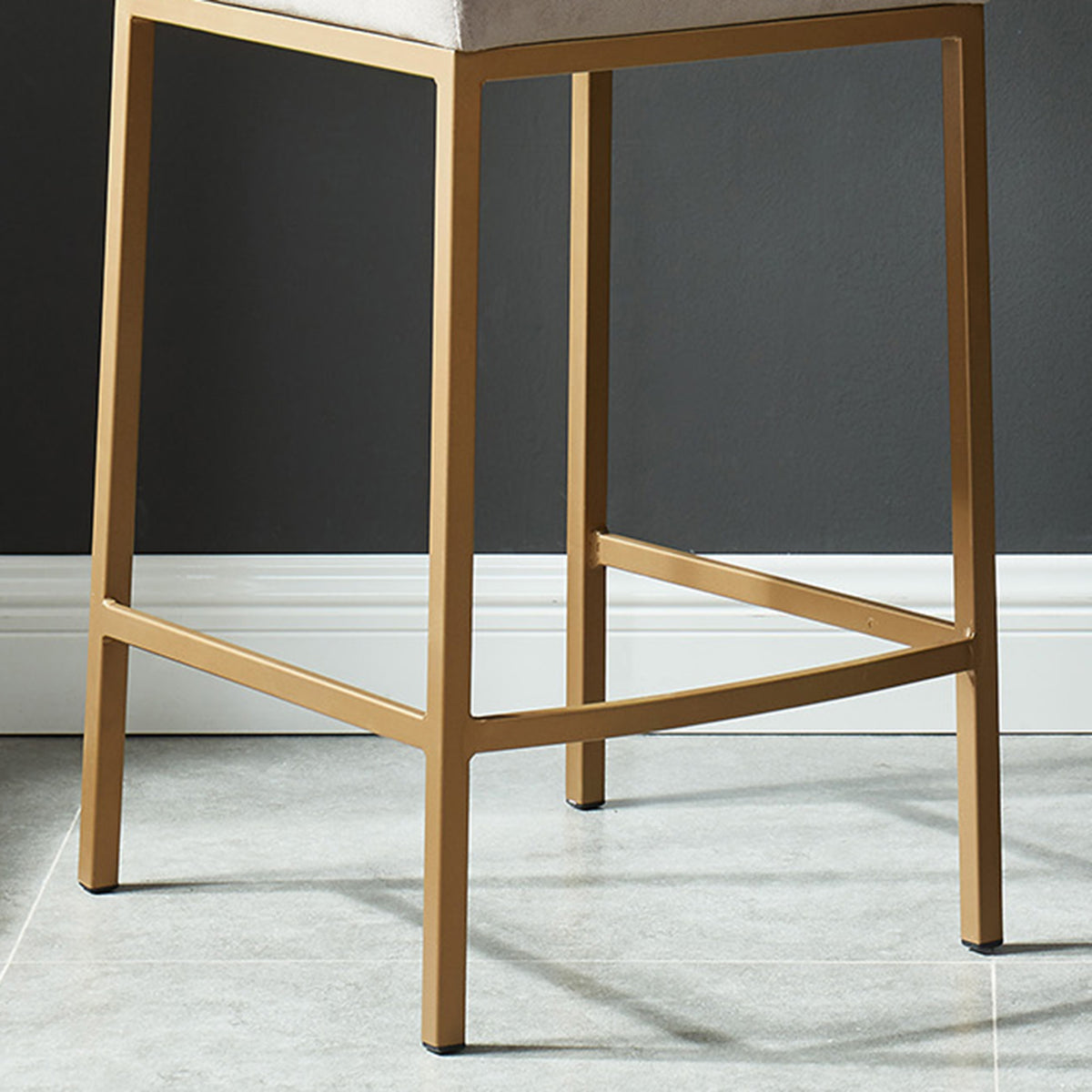 Close-up of the matte aged gold metal base and stretcher legs of the Diego 26-inch counter stool