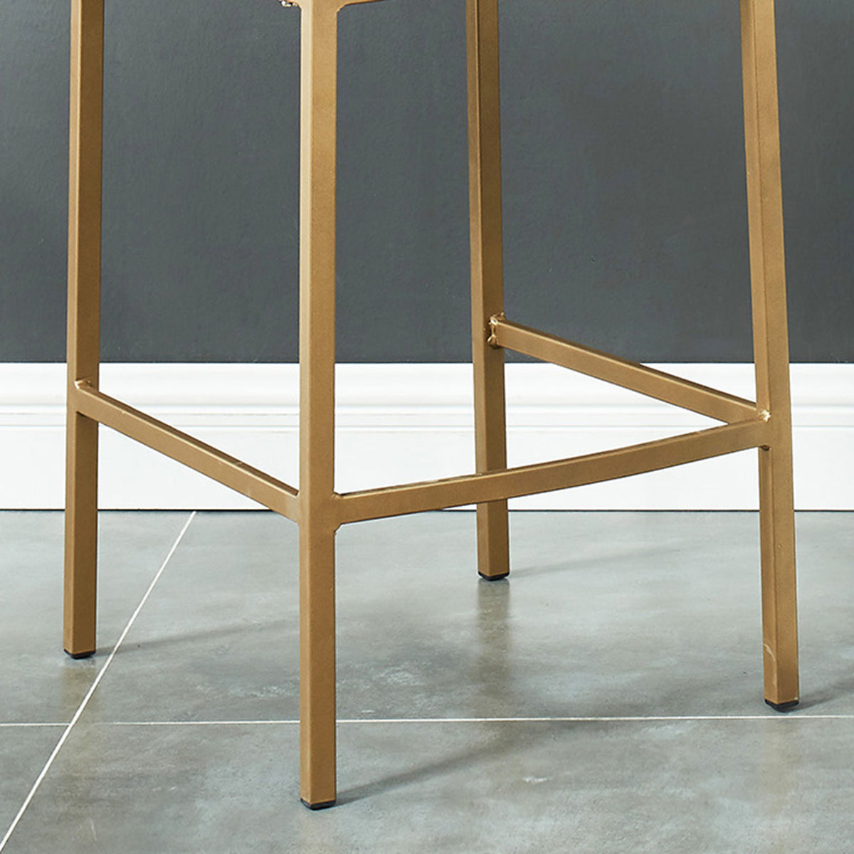 Close-up of the Diego counter stool's matte aged gold metal leg base with footrest