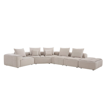 Modani Modular Sectional in beige, front view of the complete sectional with an armrest on the left, deep seat cushions and the ottoman on the right, on a white background